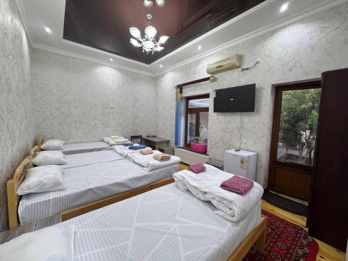 a room with three beds and a tv on the wall at Dada guest house in Bukhara