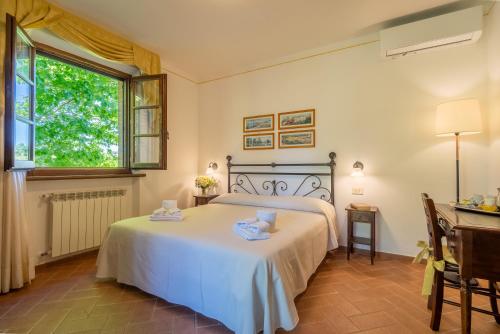 a bedroom with a bed and a desk and a window at Agriturismo Il Cavallino Saturnia in Semproniano