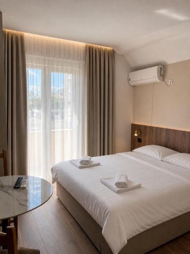 a hotel room with a large bed and a glass table at Tomm in Trebinje
