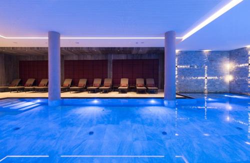 a large swimming pool with chairs in a building at Alpenhotel Ischglerhof in Ischgl
