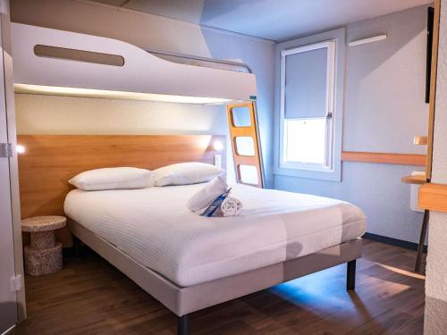 a bedroom with a large bed and a large window at ibis budget Metz Sud in Augny