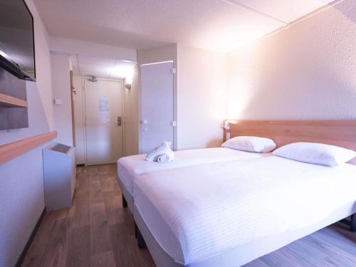 a bedroom with a large white bed and a television at ibis budget Metz Sud in Augny