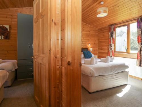 a bedroom with two beds in a wooden cabin at Elm Lodge in Keswick