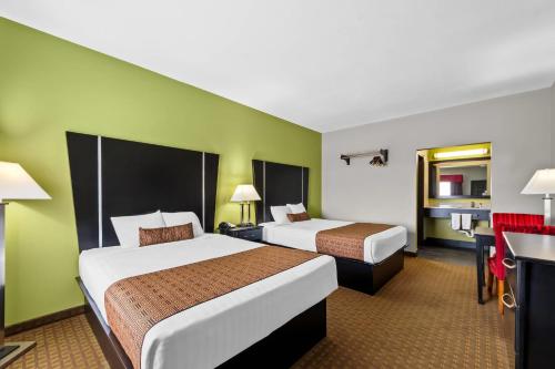 two beds in a hotel room with green walls at Rodeway Inn in Dilley