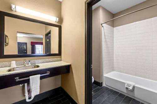 a bathroom with a sink and a tub and a mirror at Rodeway Inn in Dilley