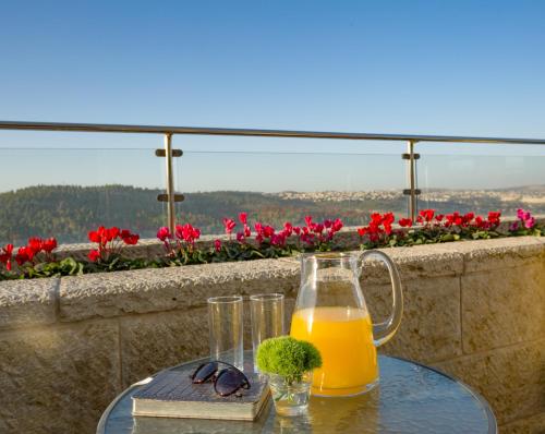 a glass of orange juice sitting on a table with a glass at Ein Kerem Hotel in Jerusalem