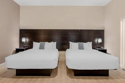 two beds in a hotel room with white sheets at Grant Street Inn, an Ascend Collection Hotel in Dunedin