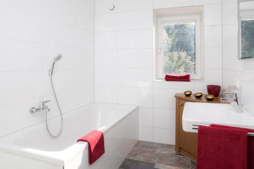 a white bathroom with a tub and a sink at Zum Hirsch in Riefensberg