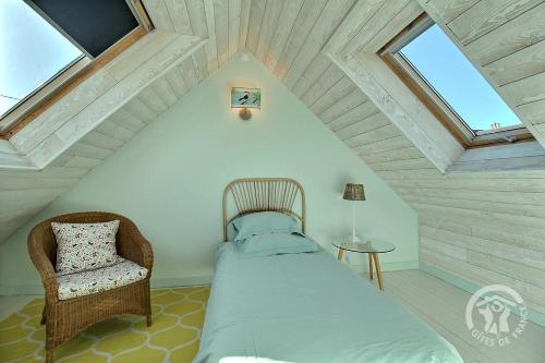 ein Schlafzimmer mit Bett und Stuhl auf dem Dachboden in der Unterkunft Les flots in Binic