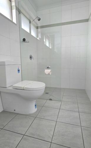 a bathroom with a toilet and a glass shower at Albatross Motel in Lakes Entrance