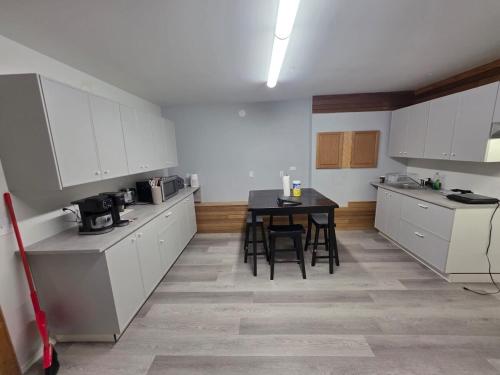 a kitchen with white cabinets and a table and chairs at Spacious 3-Bedroom Private Guest Suite in Inuvik