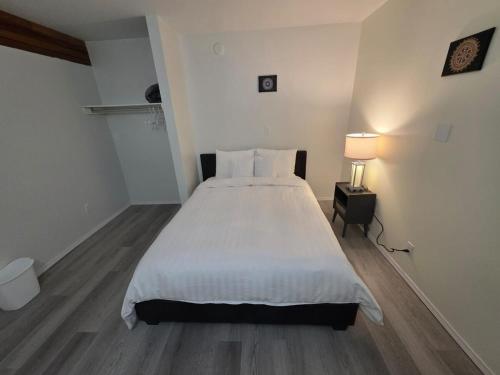 a bedroom with a white bed and a lamp at Spacious 3-Bedroom Private Guest Suite in Inuvik