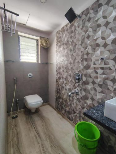 a bathroom with a toilet and a sink and a green bucket at Star Spandan in New Town