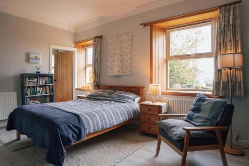 a bedroom with a bed and a chair and a window at BARHOLM CROFT Holiday Cottage in Creetown