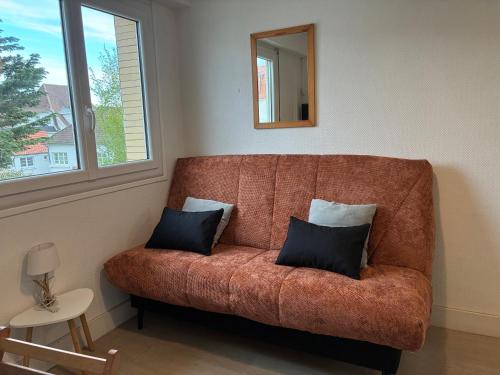 a brown couch with two pillows in a living room at Studio Cosy in Wissant