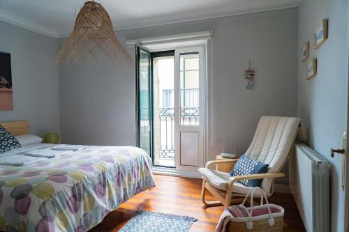 a bedroom with a bed and a chair and a window at Apartamento luminoso y espacioso en Urdaibai in Elanchove
