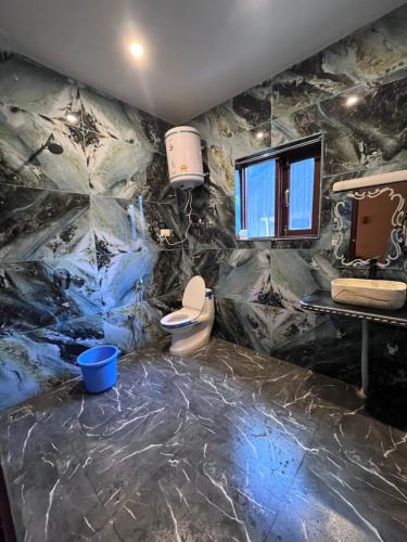 a bathroom with a marble wall with a toilet and a sink at The Walnut House in Pahalgām