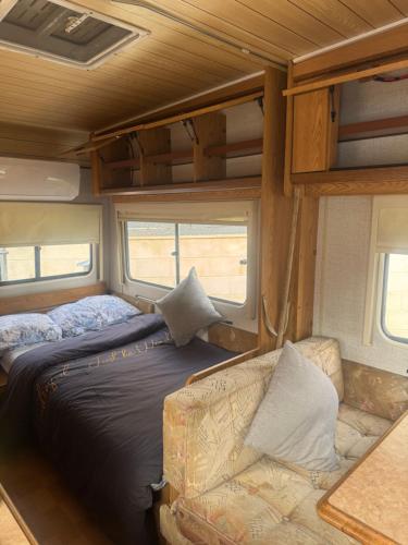 a bedroom in an rv with a bed and a couch at Caravans through the nature in Mikhmoret