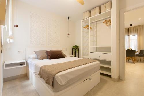 a white bedroom with a bed and a dining room at Apartamento Silleria Reyes Catolicos Centro in Granada