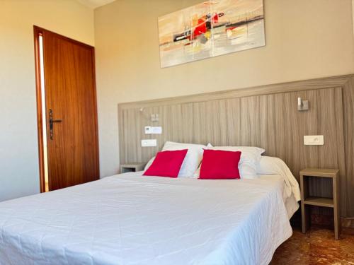 a bedroom with a white bed with two red pillows at La Maison Du Belvedere in Saint-Cyprien