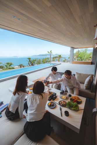 a group of people sitting around a table eating food at SHIMASTREAM house in Shodoshima