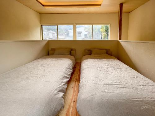 two beds in a small room with a window at Beppu TOJIHAUS 001 2min walk to Shibaseki Onsen in Beppu