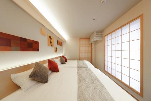 a bedroom with a large window and a bed with pillows at はく HIROSHIMA Station HOTEL in Hiroshima