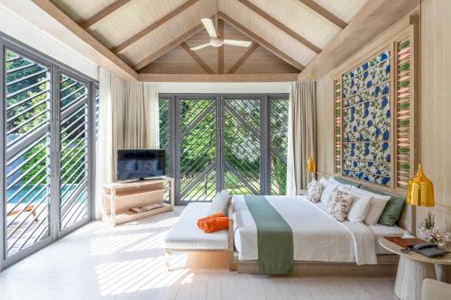 a bedroom with a bed and a tv and windows at Flora Creek Chiang Mai in Hang Dong