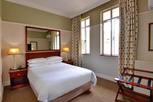 ein Schlafzimmer mit einem großen weißen Bett und einem Spiegel in der Unterkunft The Balmoral - Halaal in Durban