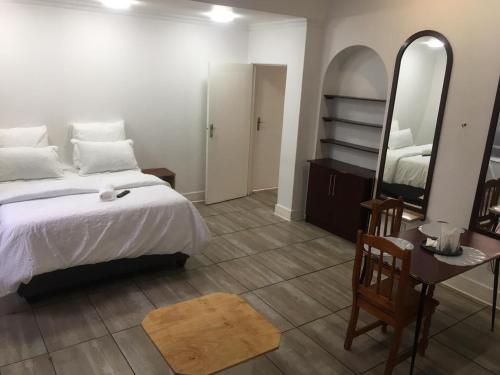 a bedroom with a bed and a table and a mirror at Zanem Guest House in Potchefstroom