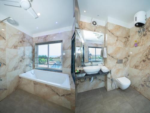 a bathroom with a tub and a sink and a toilet at Sher Bengal Beach Resort in Mandarmoni