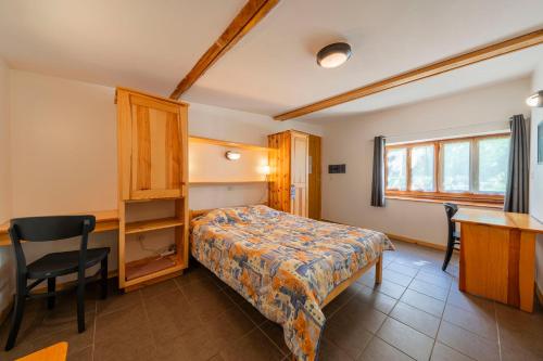 a bedroom with a bed and a desk and a table at Hôtel Engilberge in Ailefroide