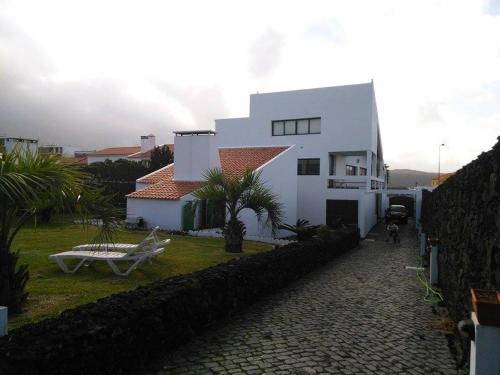 een wit huis met een tuin en een patio bij Surf & Guest Lorena´s House in Ribeira Grande