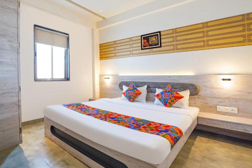 a bedroom with a large white bed with colorful pillows at FabHotel Kalptaru in Pune