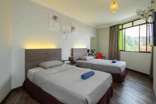 a hotel room with two beds and a window at Parkland Hotel in Brinchang