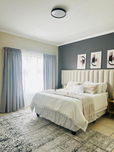 a bedroom with a large bed and a large window at Sweet Daisies Apartment in Mbabane