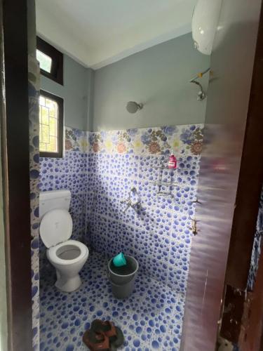a bathroom with a toilet and a blue tiled wall at Tani Adventure in Ziro