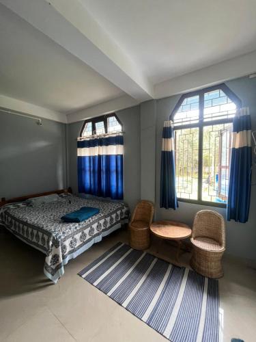 a bedroom with a bed and two windows and a rug at Tani Adventure in Ziro