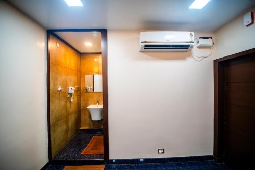 a bathroom with a toilet and a air conditioner on a wall at V V Residency in Thanjāvūr