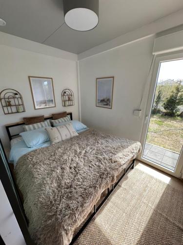 a bedroom with a large bed with a large window at Baltic Lark Gąski domek 30m2, taras zadaszony 27m2 ogródek klimatyzacja in Gąski