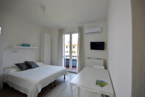 a white bedroom with two beds and a table at Casavacanze Zeus in Marciana Marina