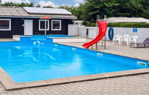 a red slide in a swimming pool with a house at Cozy Apartment In Farsø With Heated Swimming Pool in Farsø