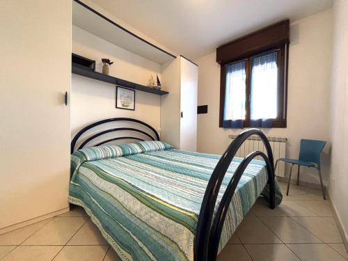 a bedroom with a bed and a window and a chair at Residence Corallo con piscina in Rosolina Mare