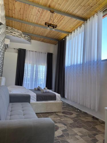a bedroom with two beds and a couch and windows at Villa Neimi in Ksamil