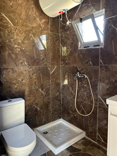 a bathroom with a shower with a toilet and a window at Villa Neimi in Ksamil