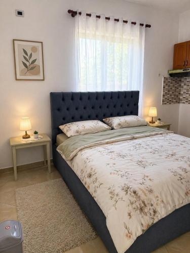 a bedroom with a bed with a blue headboard and a window at Airport Double Room in Kamëz