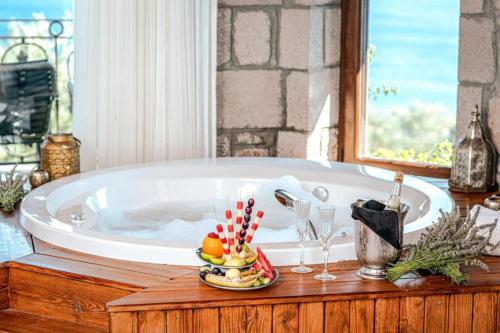a bath tub with a bowl of fruit and wine glasses at Assos Dionysos Special Class Hotel Adults Only 12 years in Behramkale
