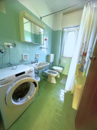 a bathroom with a washing machine and a toilet at NAONIS - Appartamenti in Bibione