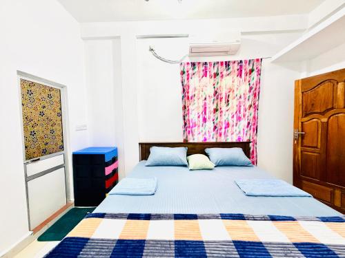 a bedroom with a bed with a checkered blanket at Green House Holiday Villa in Trincomalee