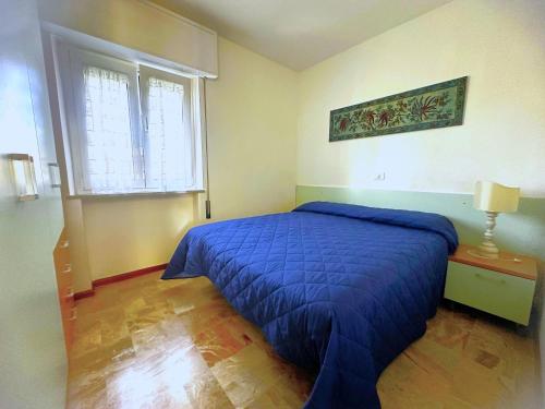 a bedroom with a blue bed and a window at NAONIS - Appartamenti in Bibione